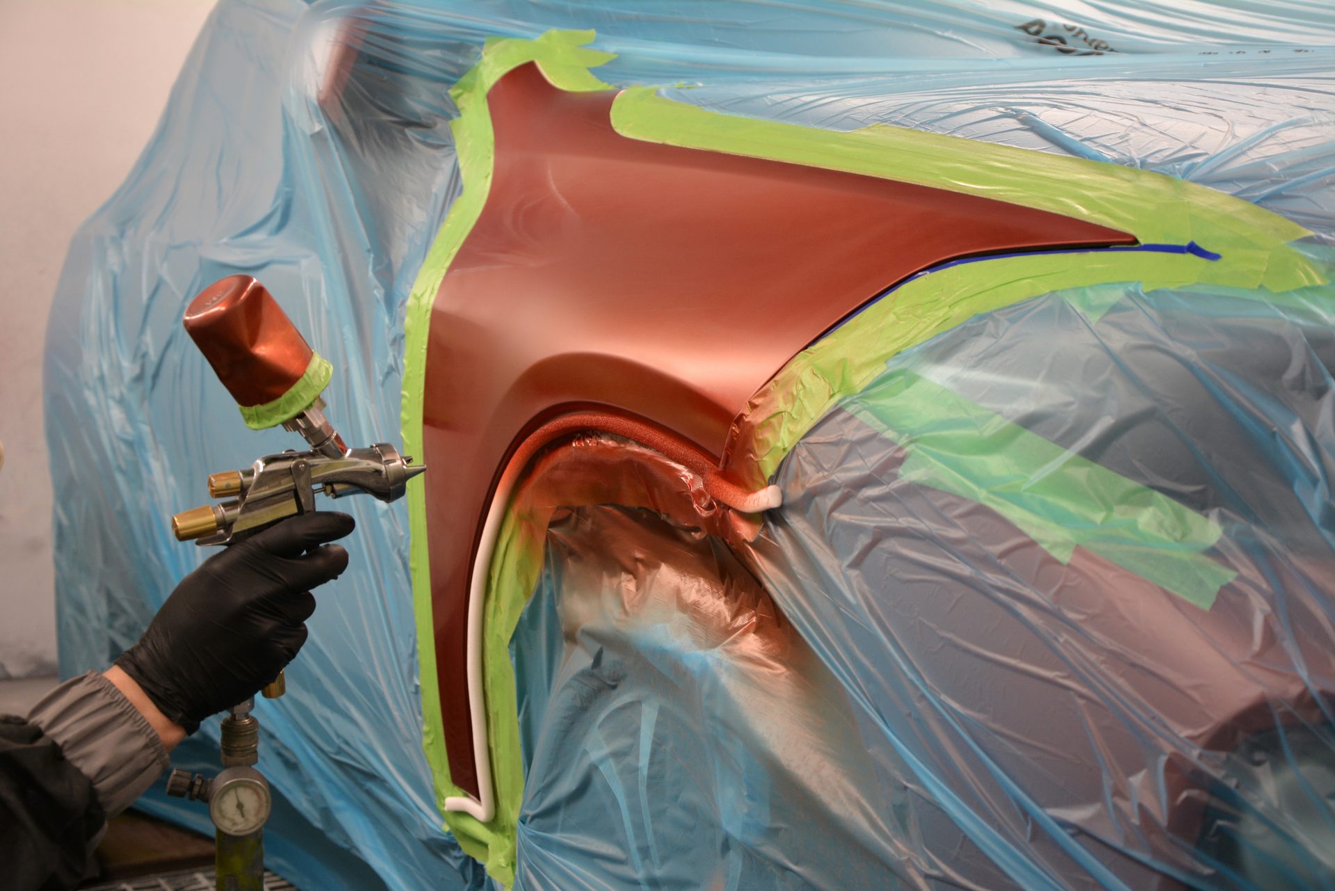 Abgeklebter Kotflügel wird bei der Stiller GmbH in rotem Metallic-Lack gespritzt
